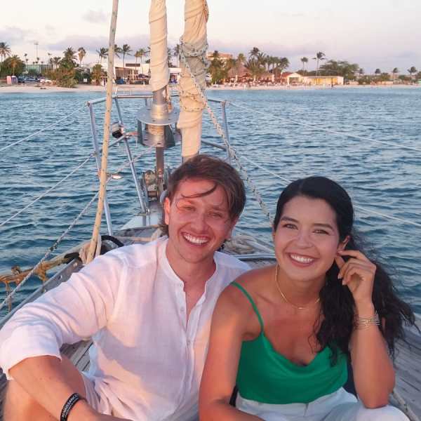 a woman standing in front of a boat next to a body of water